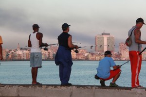 Local men fish along the Malecon at sunrise. 